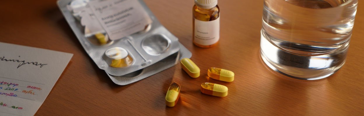 На столе лежат таблетки и стакан воды